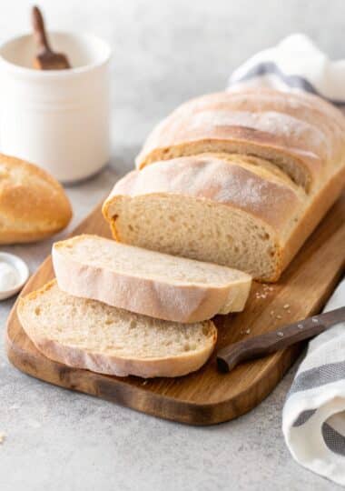 A stunning, golden italian bread recipe loaf on a wooden board.