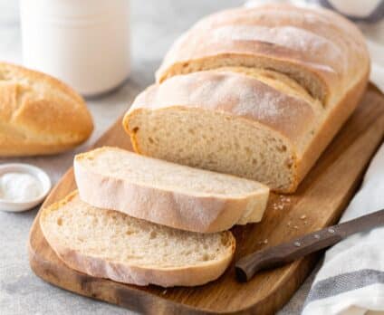 A stunning, golden italian bread recipe loaf on a wooden board.