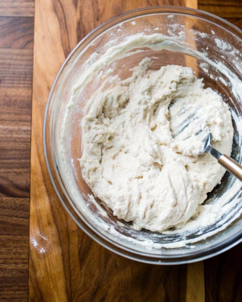 hands dimpling sourdough focaccia dough before baking